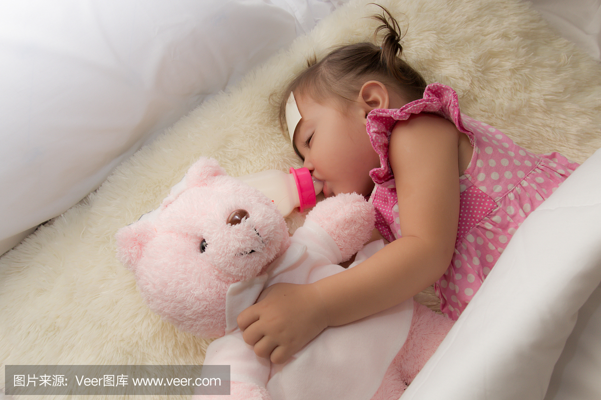 婴儿从一个小瓶子里喝水或喝牛奶,躺在床上,同