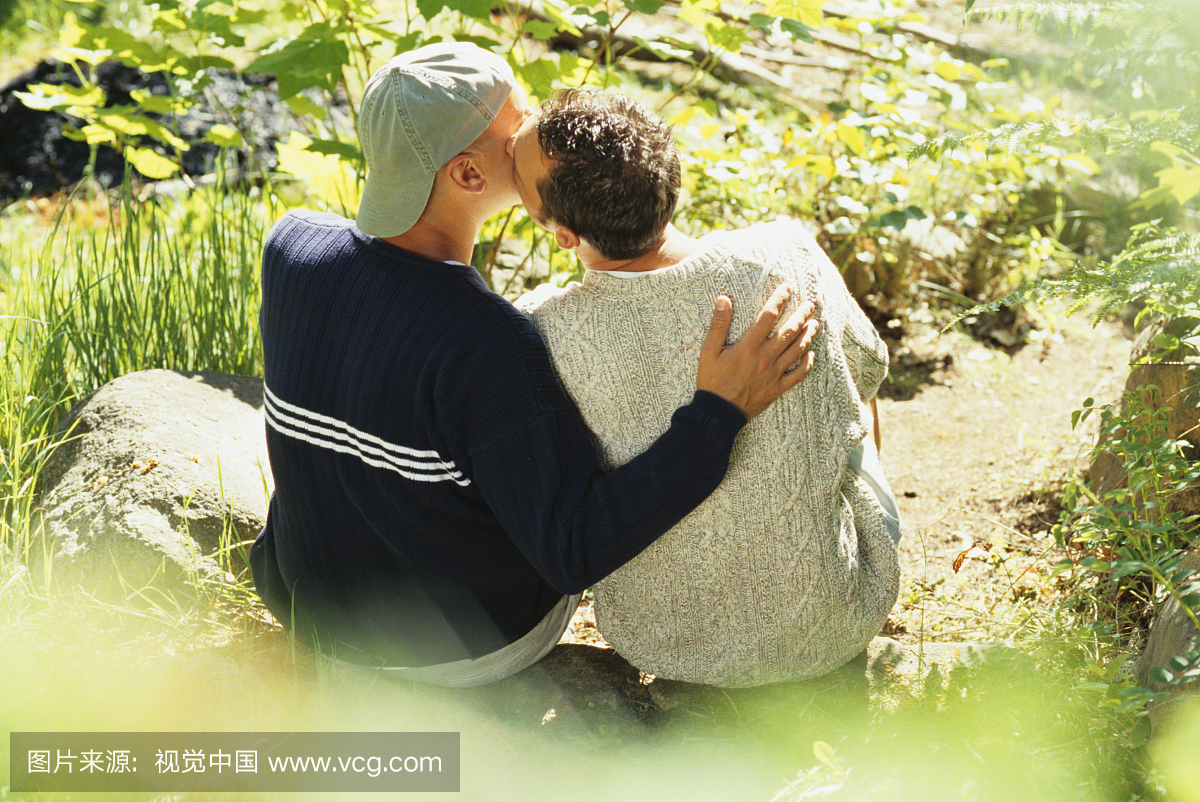 同性恋情侣接吻在花园里的岩石上