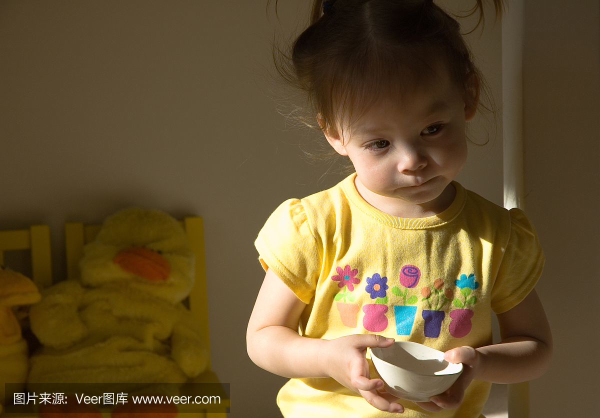 饥饿的女孩小孩在她的房间里拿着空碗