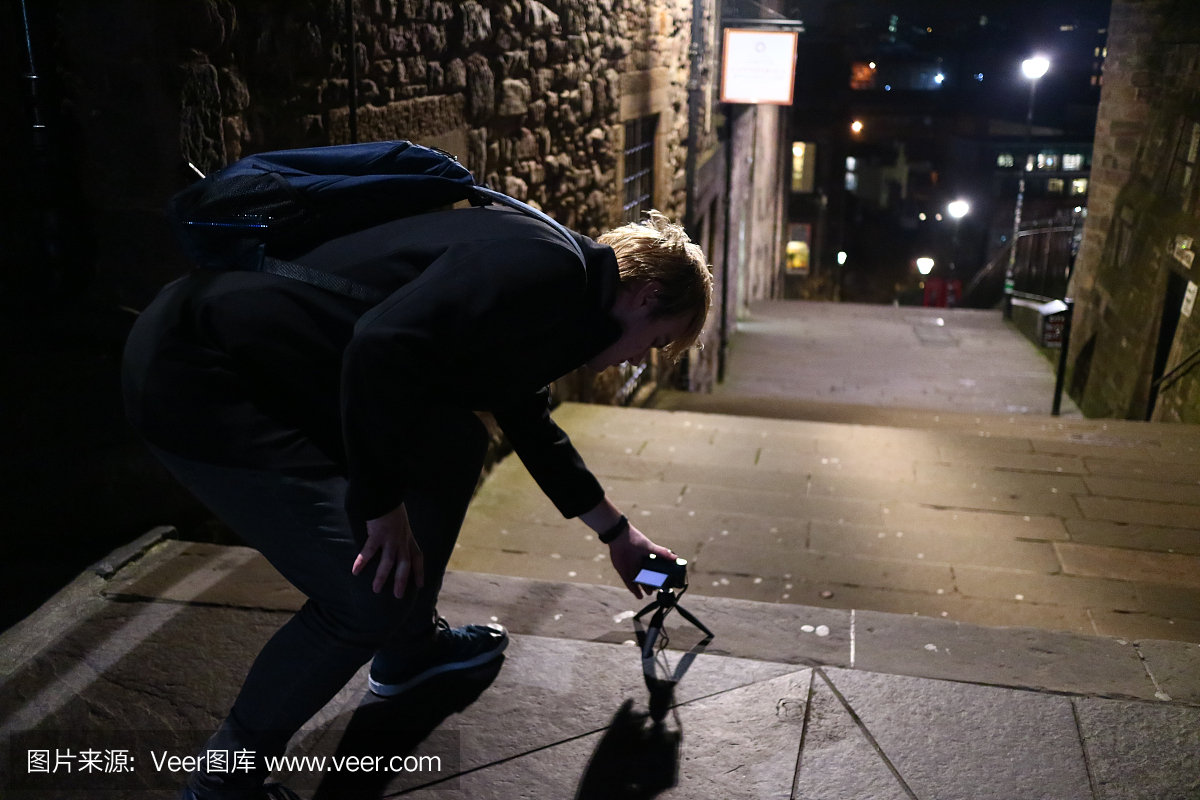 一名年轻男子在晚上在爱丁堡街头拍摄婴儿三脚