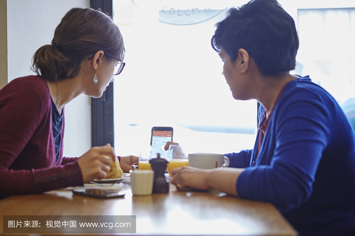 两名女子在餐厅读取智能手机文字