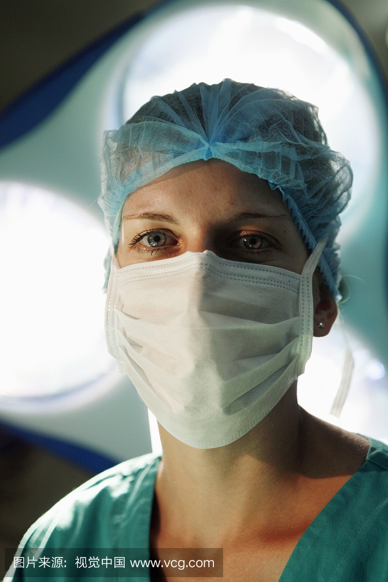 女外科医生从外科手术灯下方直接看着相机