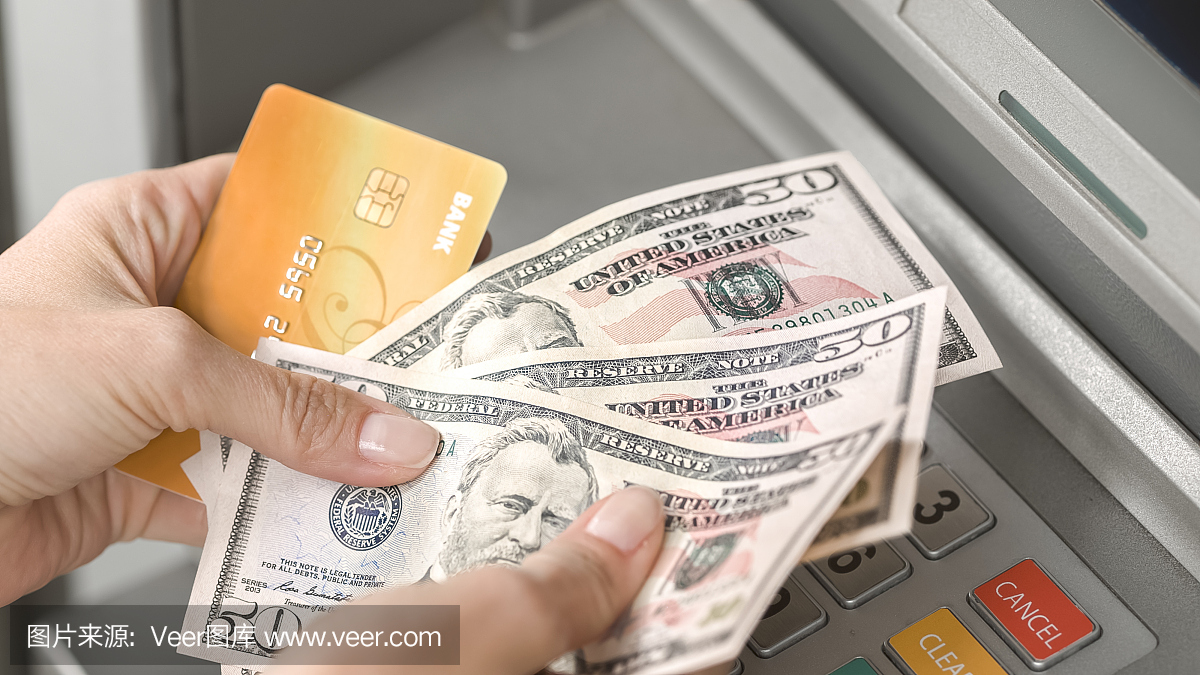 女人从自动提款机取出钱在ATM上,计数它