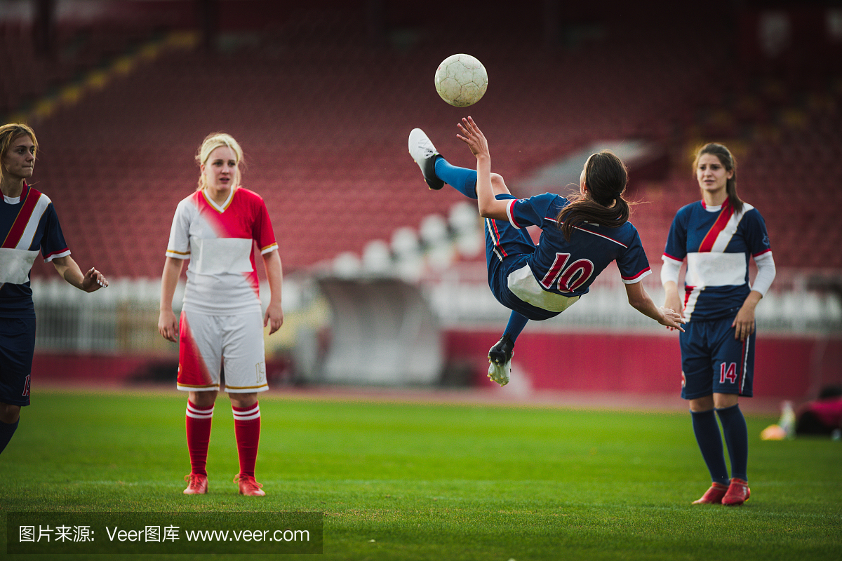 熟练的女足球前锋在比赛期间做自行车踢。