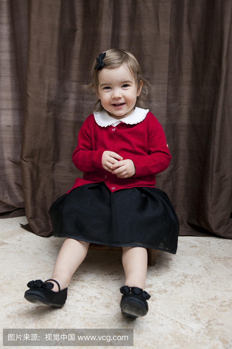 婴儿白种人女孩,1岁,坐在红色和黑色假期礼服