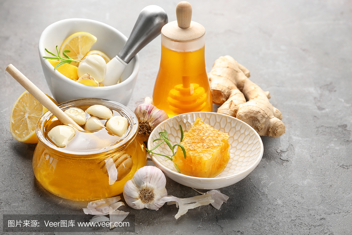 蜂蜜和大蒜作为自然感冒药在灰色带纹理的背景