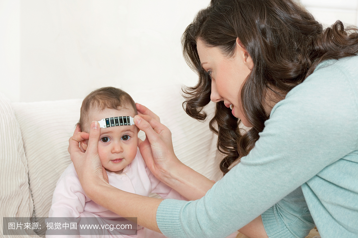 母亲测量宝宝额头上的温度