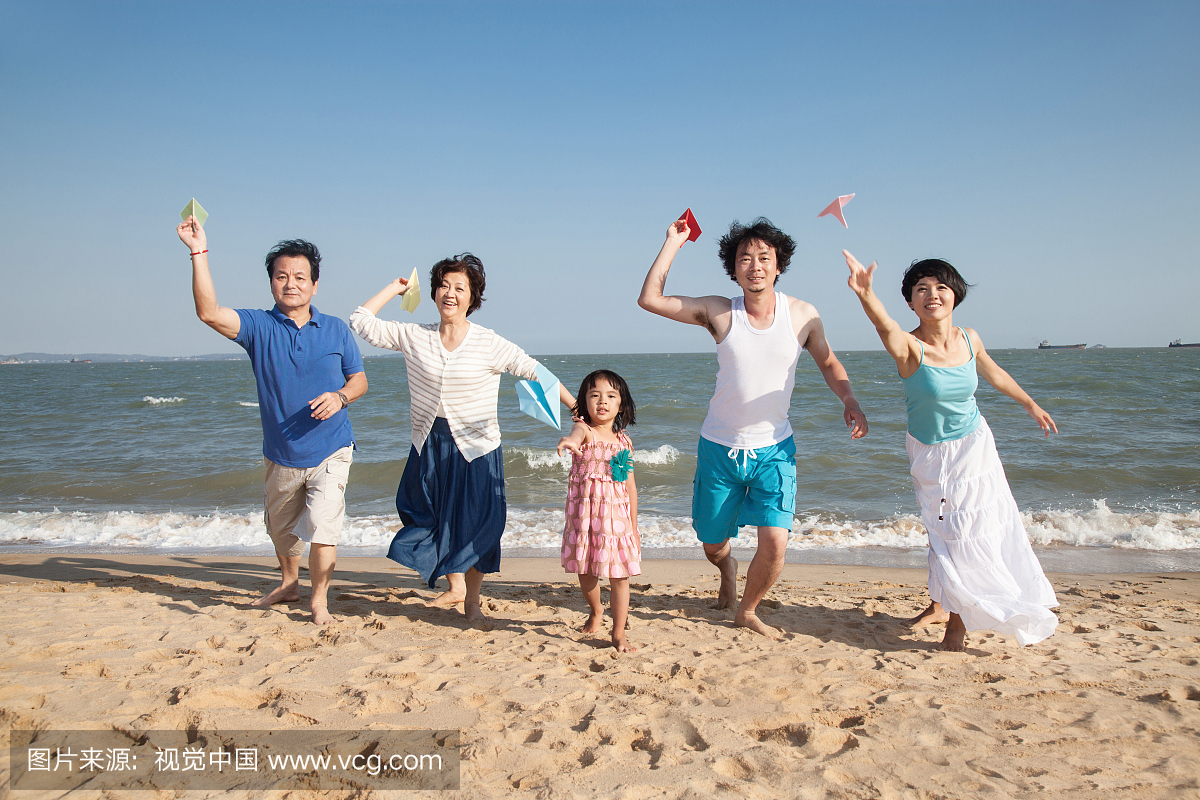 一家人在沙滩上玩纸飞机