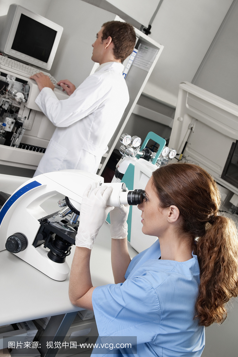 女实验室技术人员通过显微镜分析样品