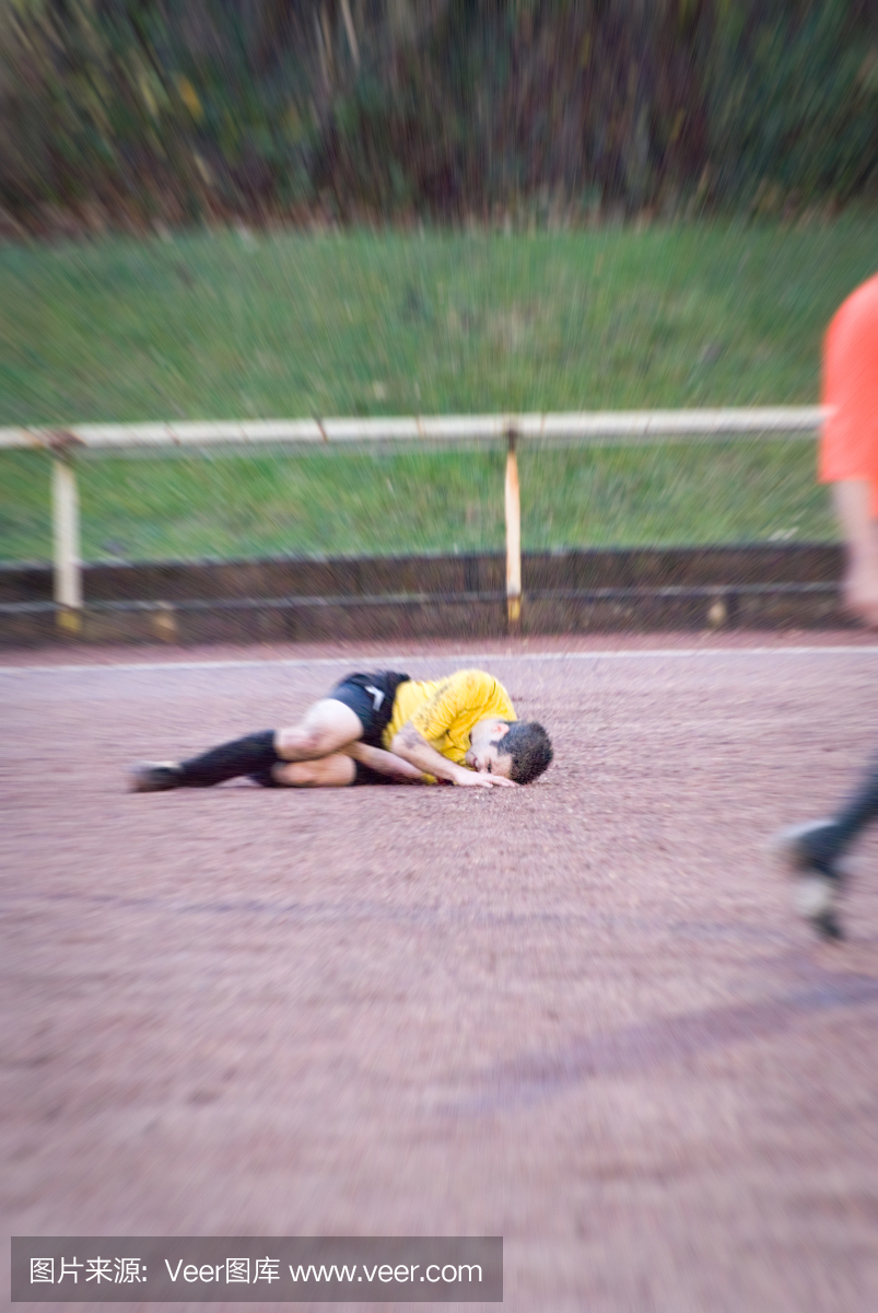 足球运动员在足球比赛中犯规,躺在田野上
