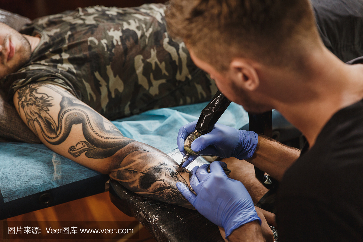 专业tattooer艺术家由机器黑色墨水从瓶子上做