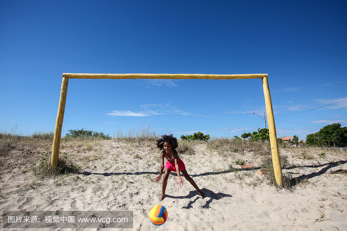 在沙滩上踢足球的黑人女孩