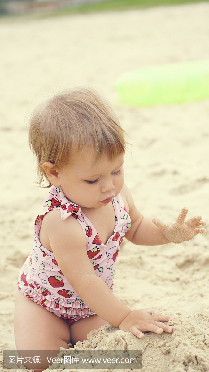 小宝贝男孩坐在沙滩上。节日快乐