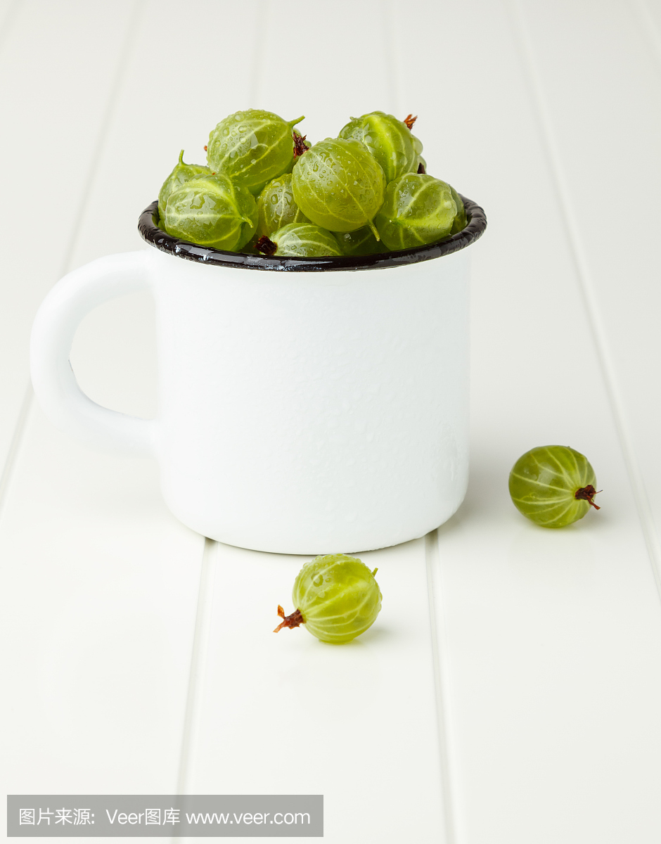 Fresh green gooseberries in an enamel mug on