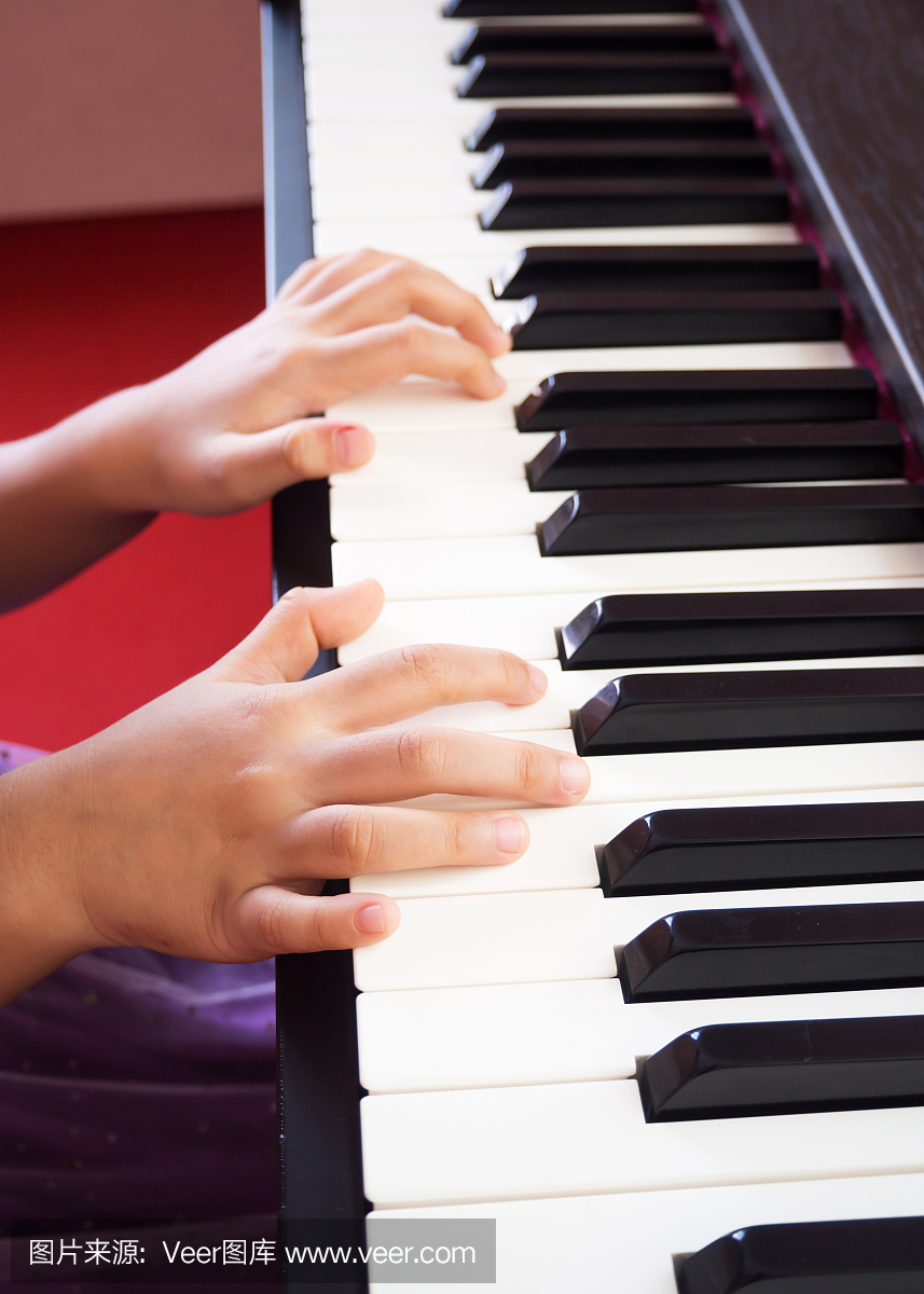 弹钢琴的女孩。特写手和手指。儿童学习喜爱的