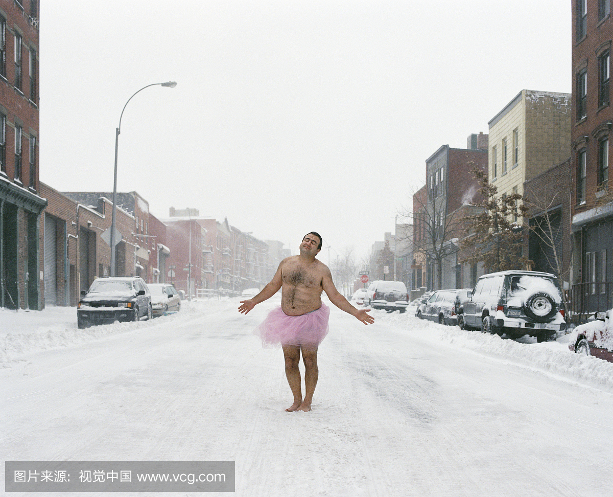 男子穿着芭蕾舞演员走在雪覆盖的街道,冬天