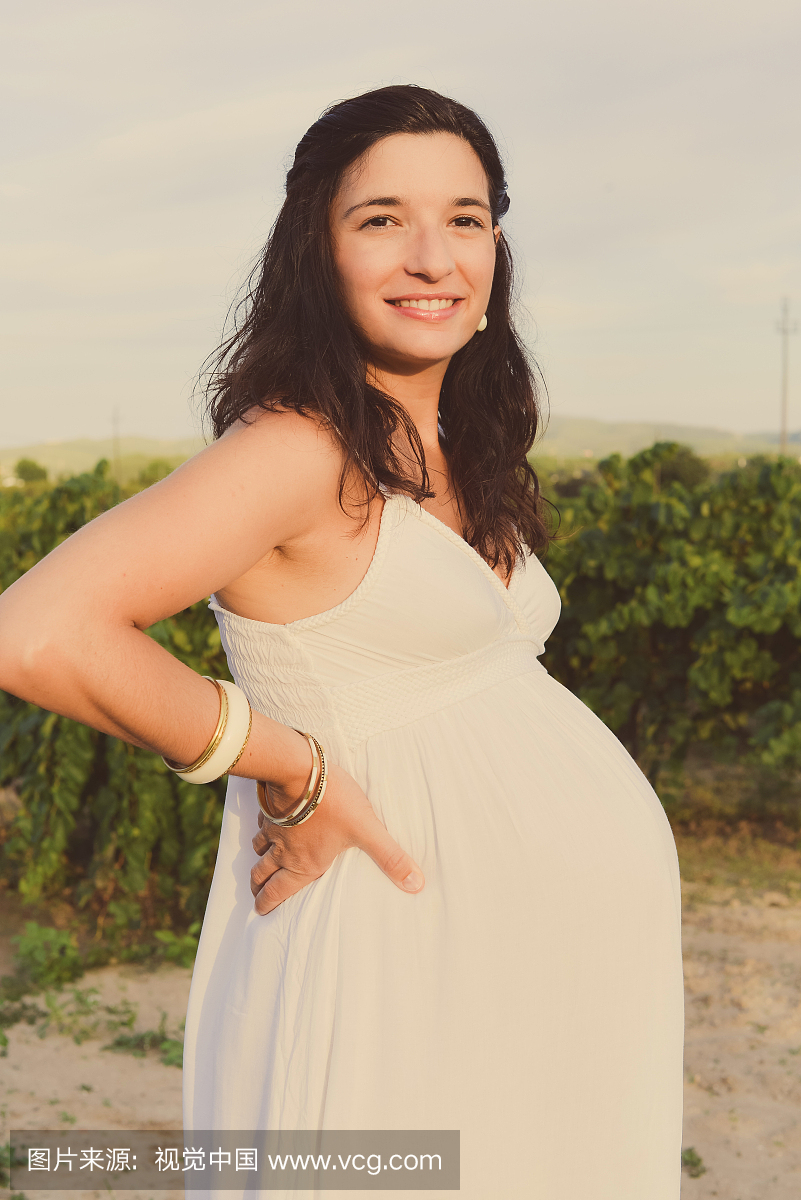 快乐的九个月孕妇旁边的葡萄园