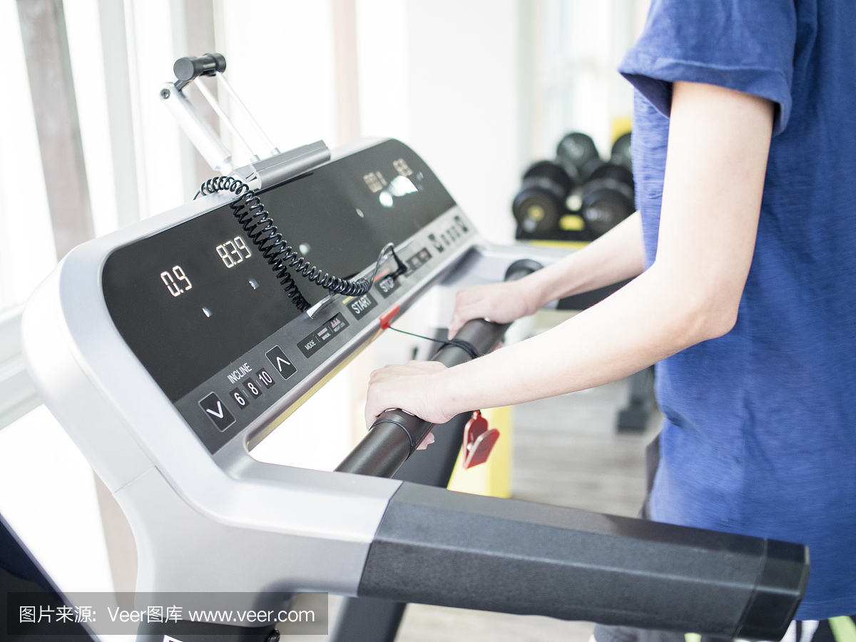 女孩跑在跑步机上。关闭在上身拍摄。