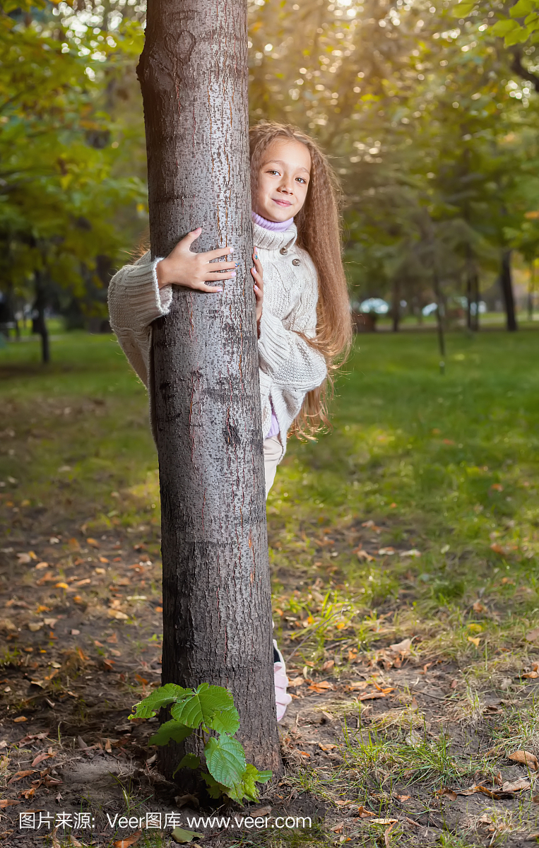 漂亮的小女孩在白色的毛衣摆在秋天公园