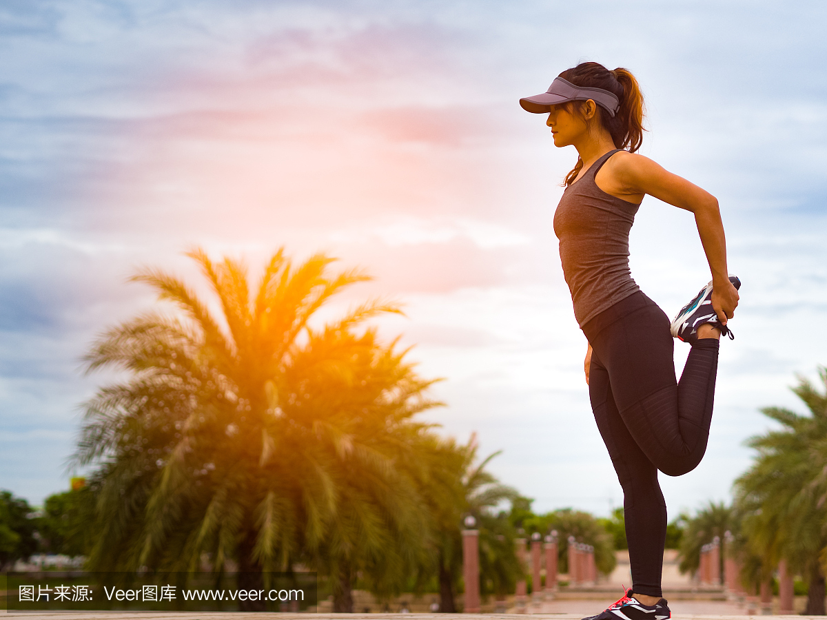 运动的女人拉伸腿和大腿后跑步在户外公园在日