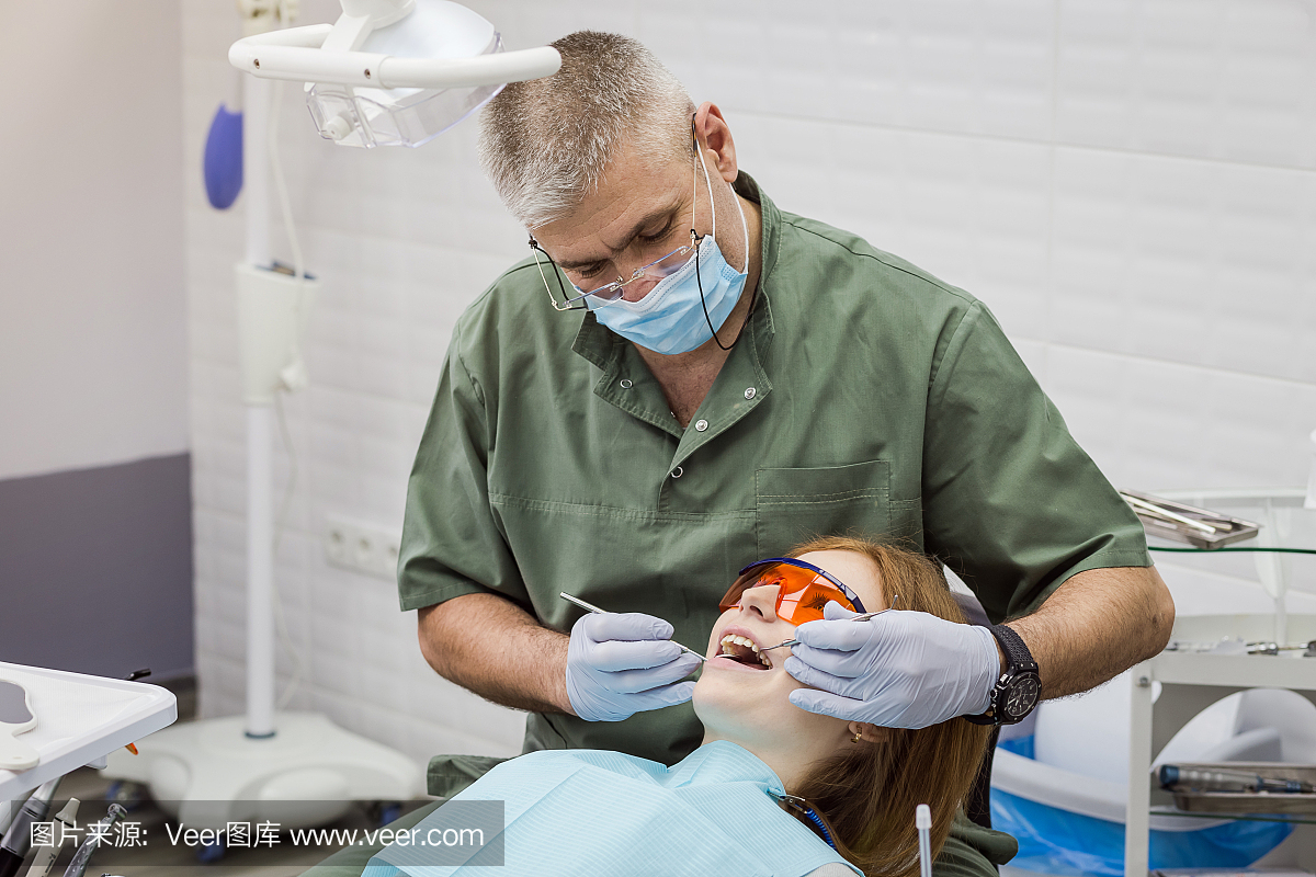 Dentist examining girl's teeth in clinic. Dental pr