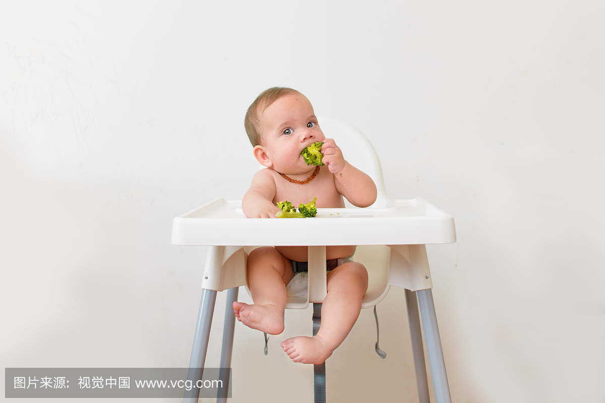 婴儿吃西兰花坐在高脚椅上