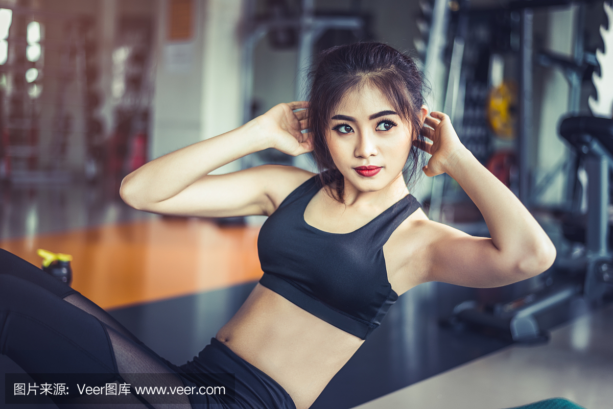 亚洲健身女孩做紧缩扭曲在健身房的侧视图。体