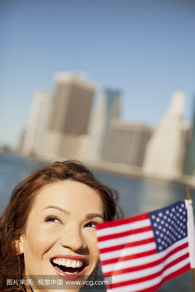 Woman waving American flag by city cityscape
