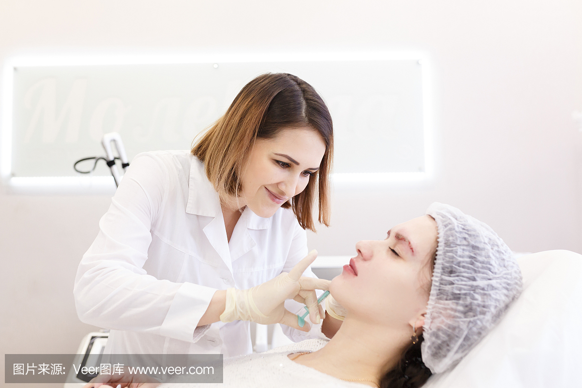 美丽年轻的医生美容师做填充注射在嘴唇。美容