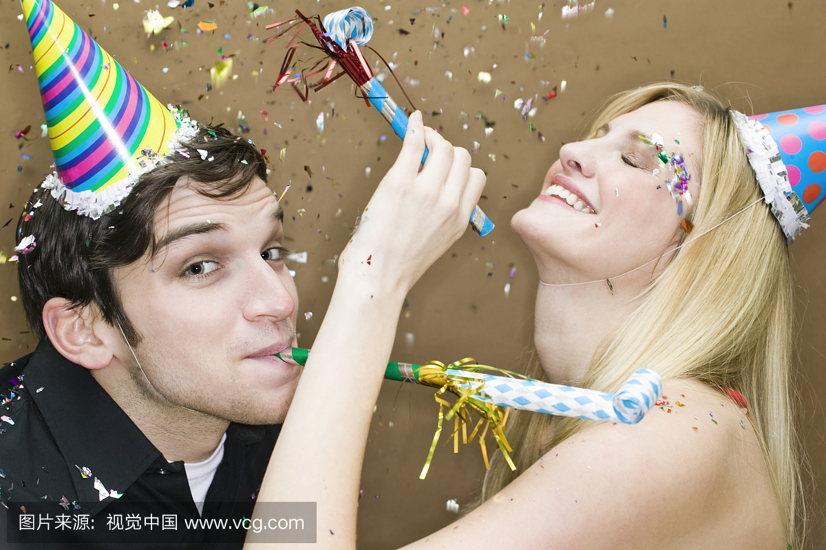 戴着派对帽子的夫妇,带着鼓风机