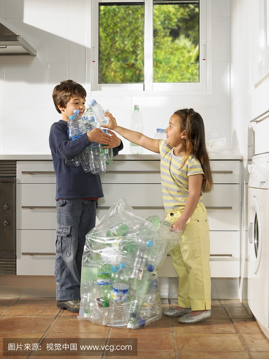小男孩(6-8岁)和女孩(4-6岁)在厨房里分享回收