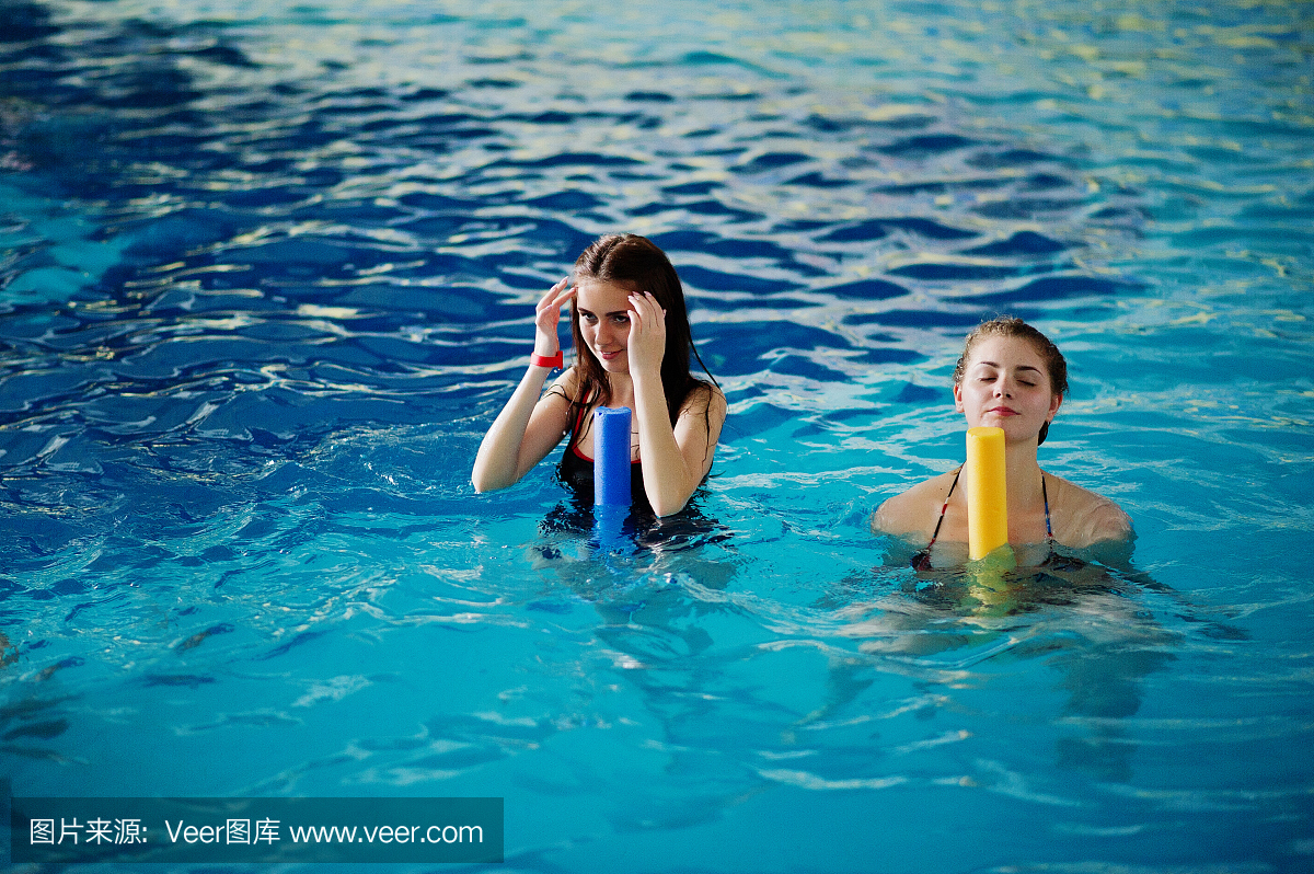 健身小组的女生在水上公园游泳池做有氧运动。