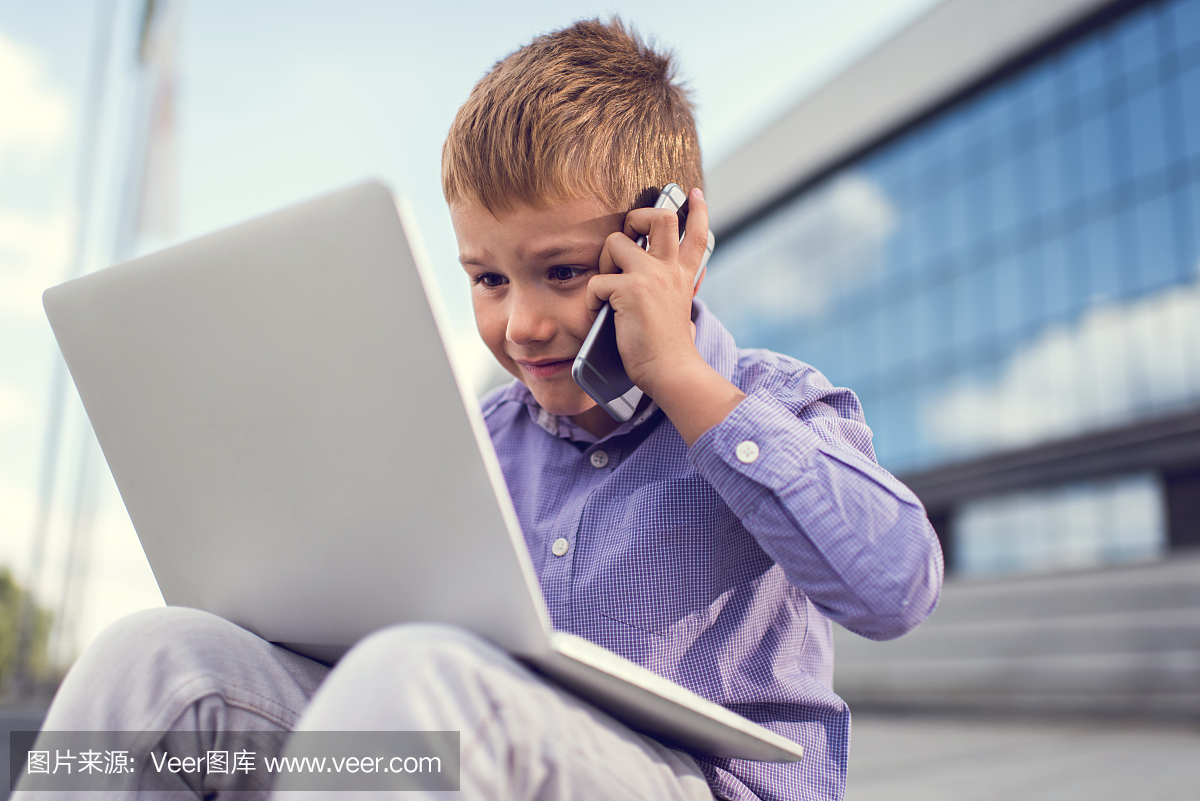 忙碌的商务男孩在手机上谈话时使用笔记本电脑