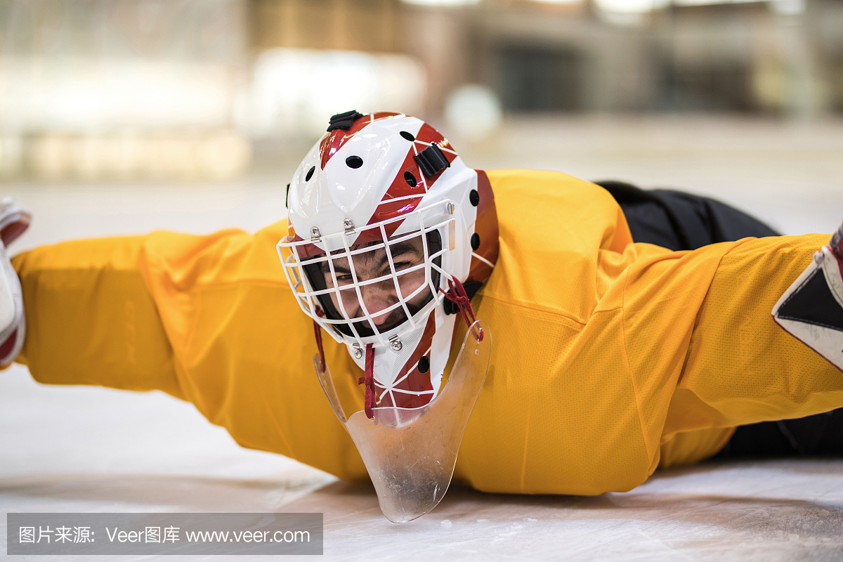 顽皮的冰球守门员开心,同时躺在溜冰场的冰上