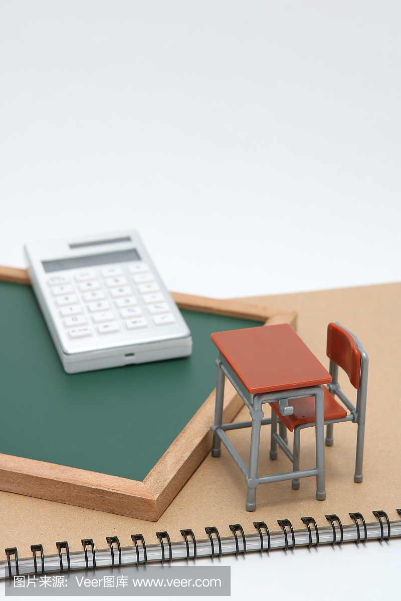 微型学校书桌,黑板和白色背景上的计算器。