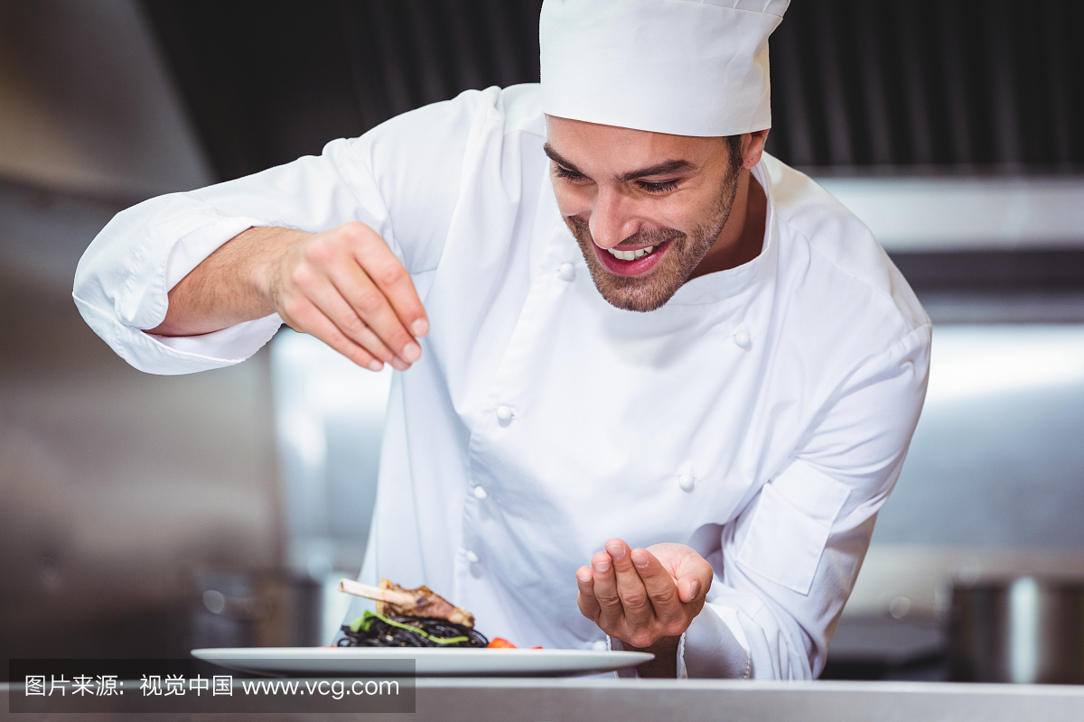 Chef sprinkling spices on dish i