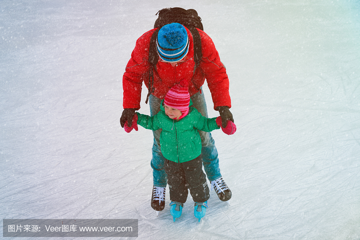 父亲和小女儿在冬天学习滑冰