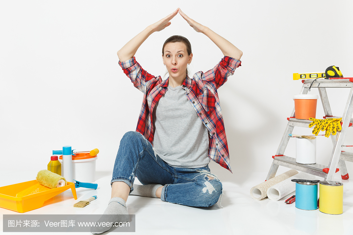 女人用手显示房子的屋顶,坐在地板上用仪器为