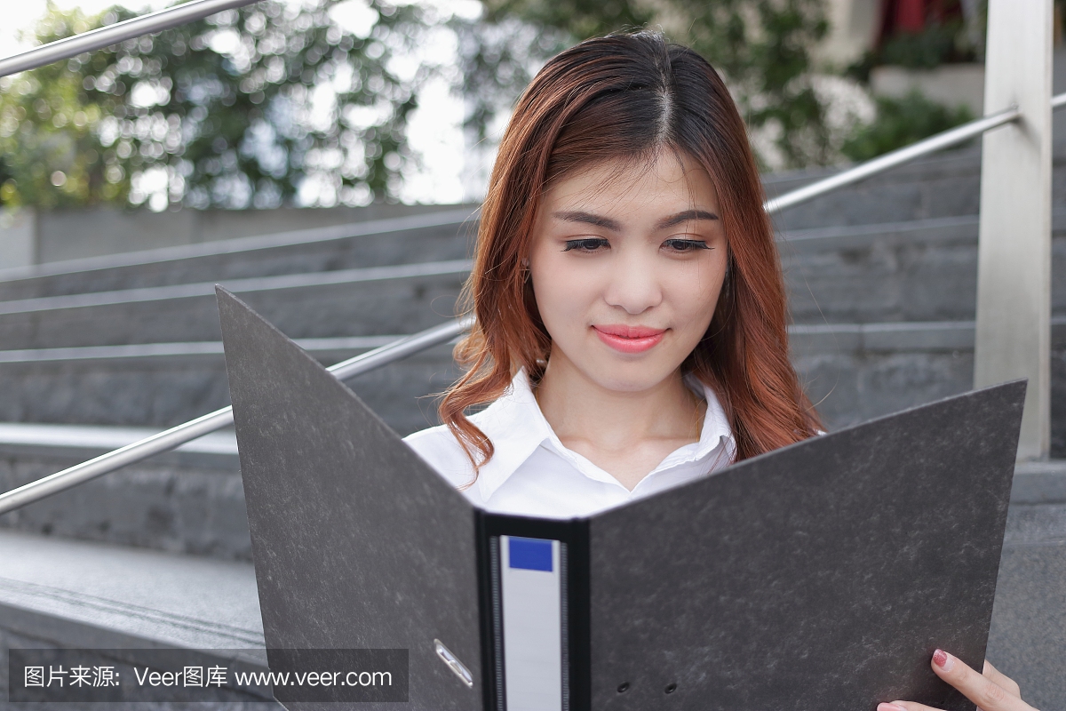 关闭年轻的亚洲业务女人看文件纸上环活页夹