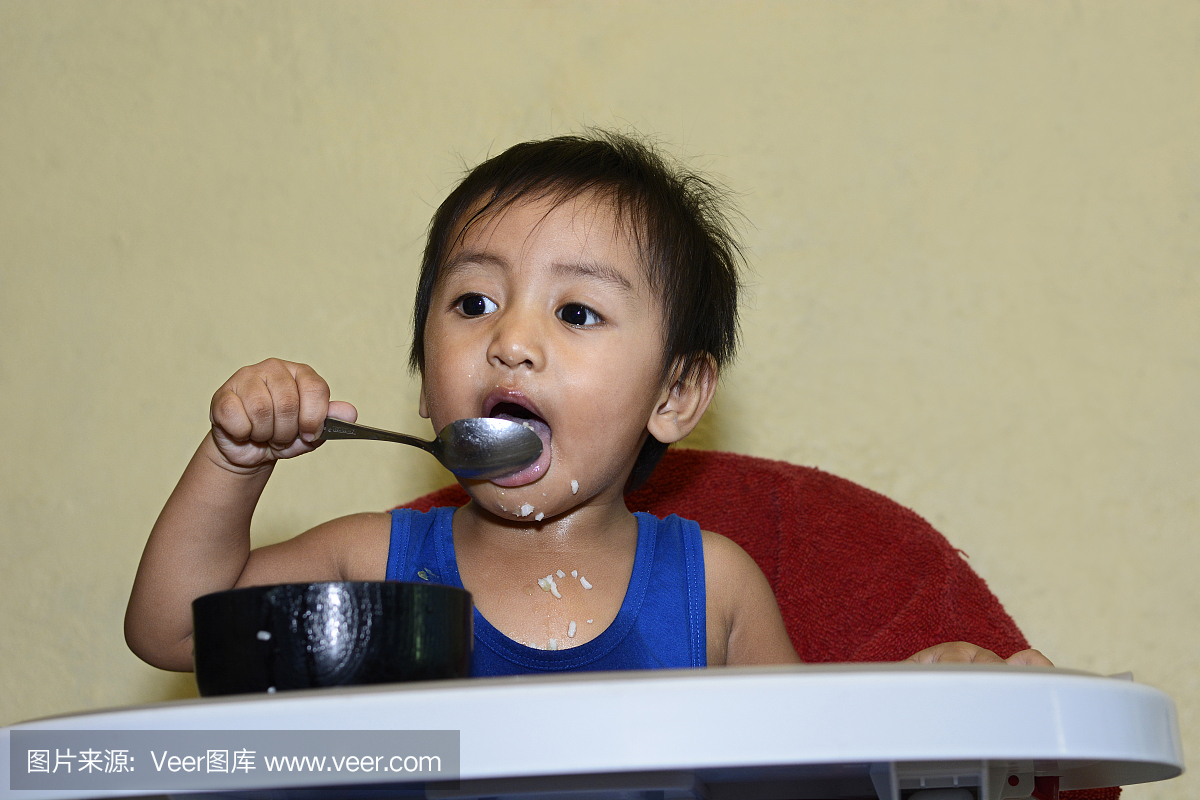 1岁的小男孩学会用勺子吃饭
