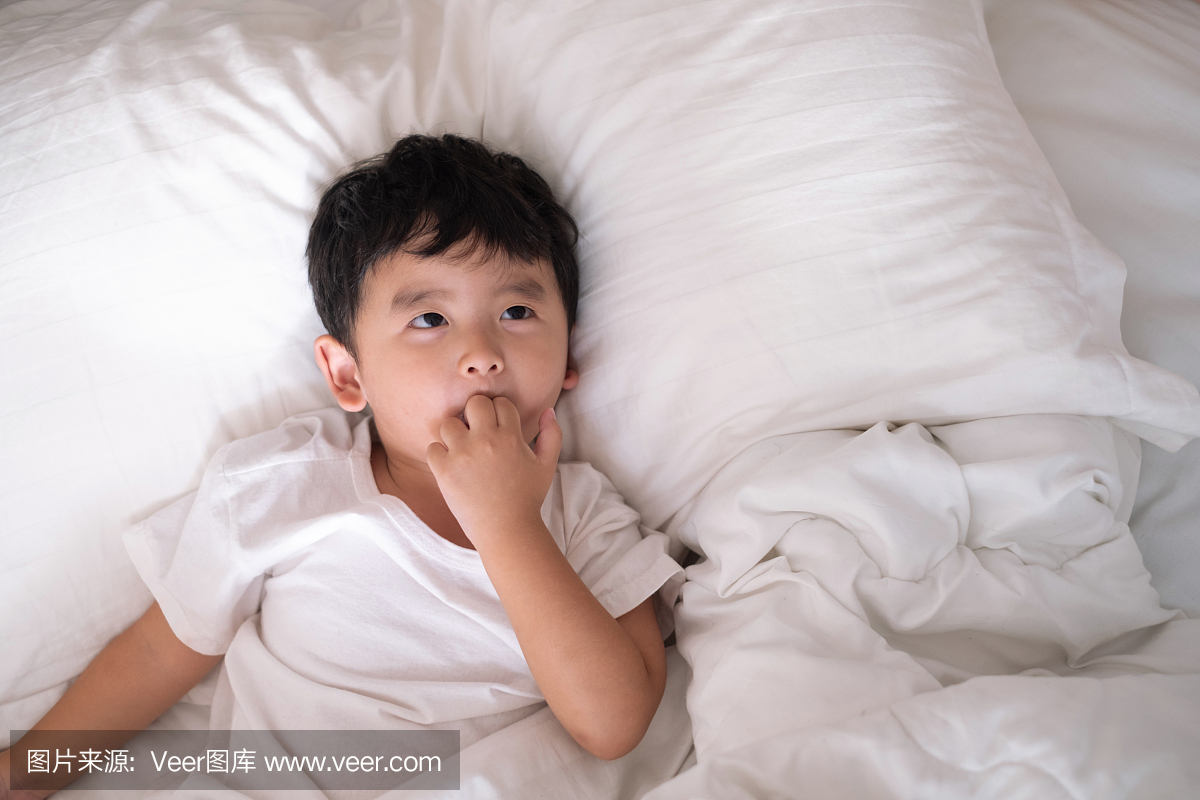 3岁的小可爱亚洲男孩在家里的白色衬衫在床上