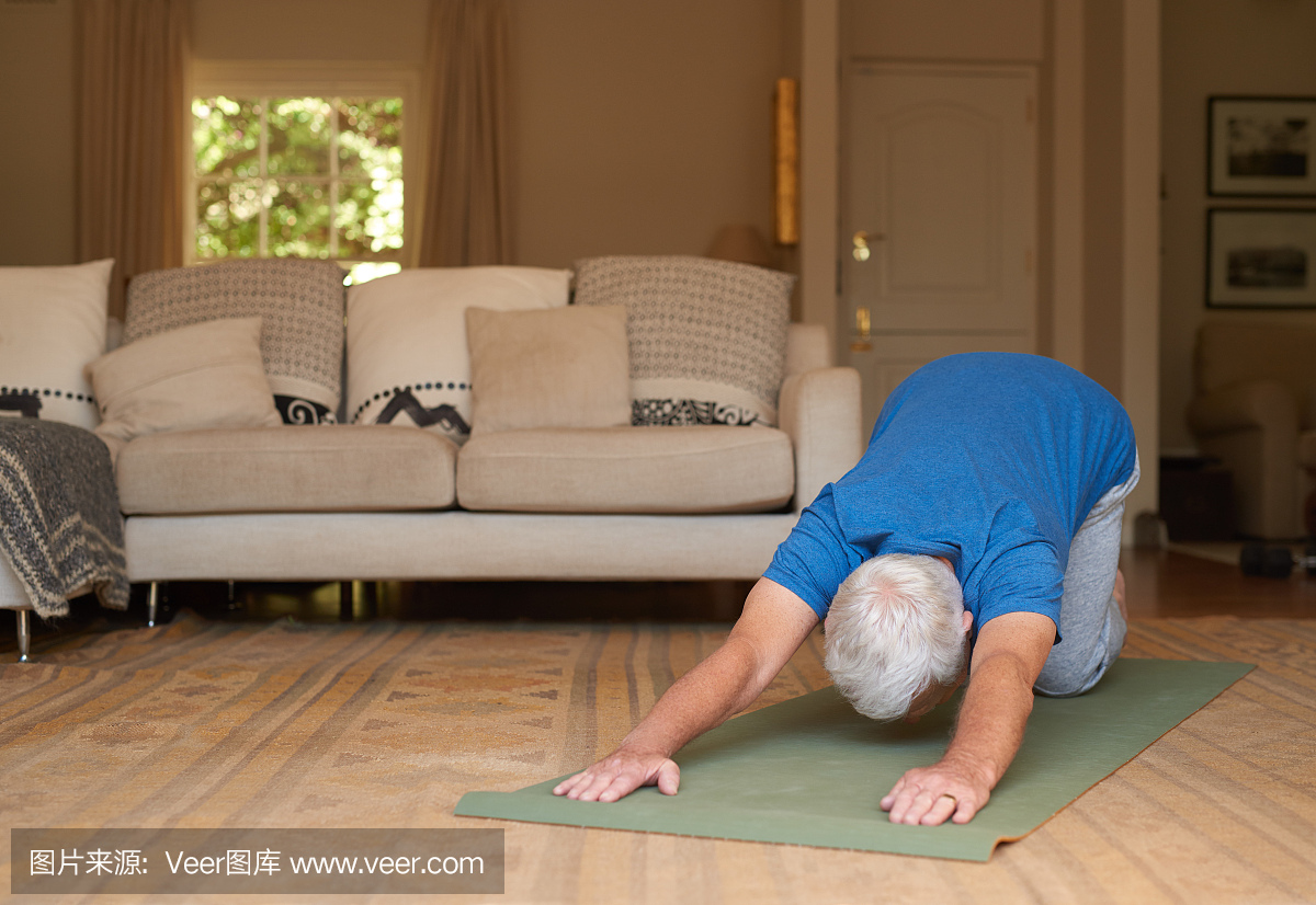 活跃的老人在家里坐瑜伽垫锻炼身体