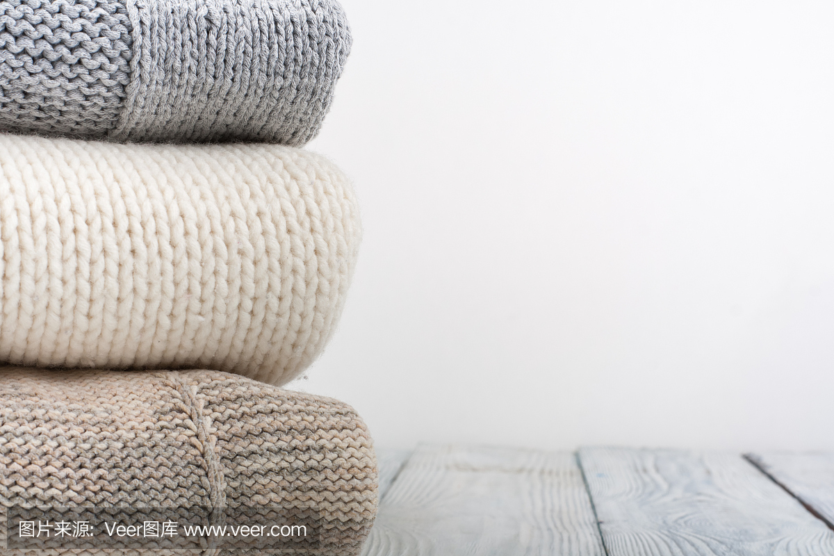 针织羊毛毛衣。堆的针织的冬季衣服在木制的背