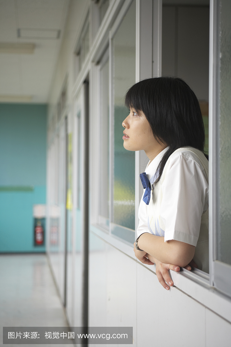 十几岁的女孩(13-15岁)倾斜在学校走廊的门槛