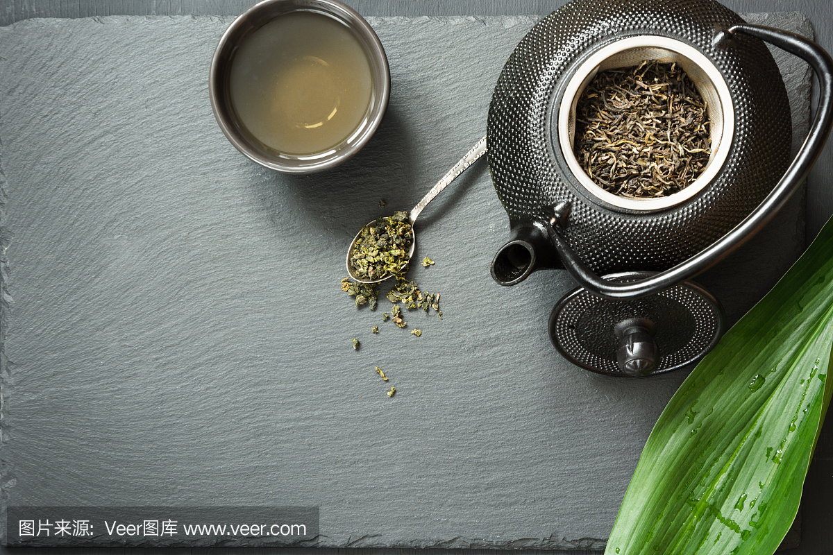 绿色日本茶在黑色的石板上。与干绿茶的黑色茶