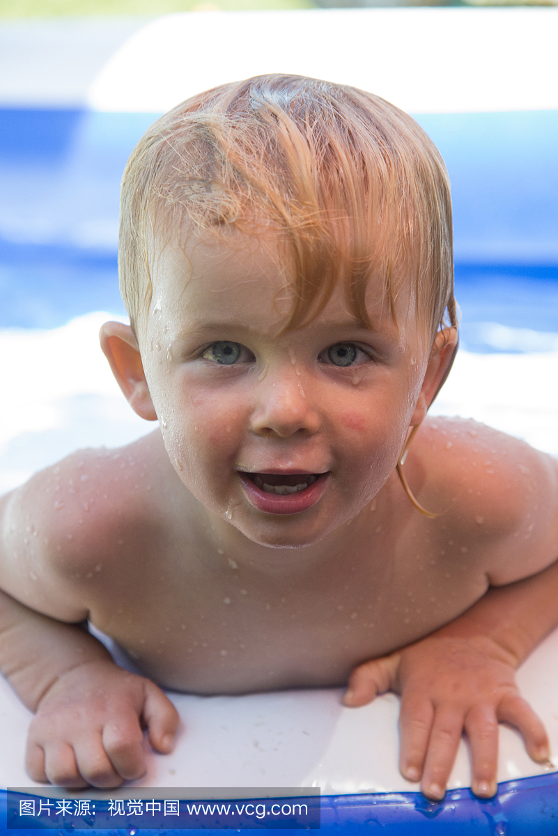 一个两岁的男孩在一个游泳池的浮动玩具。