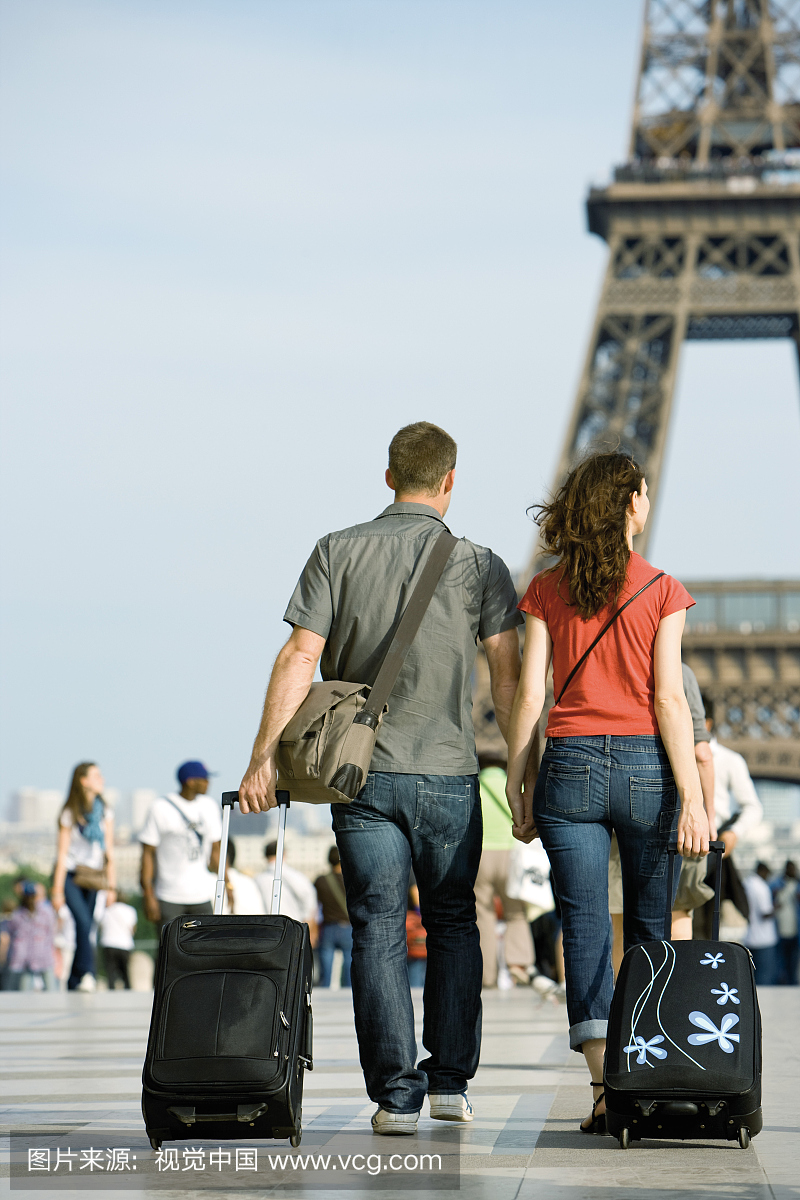 夫妇走在埃菲尔铁塔附近的行李箱,巴黎,法国