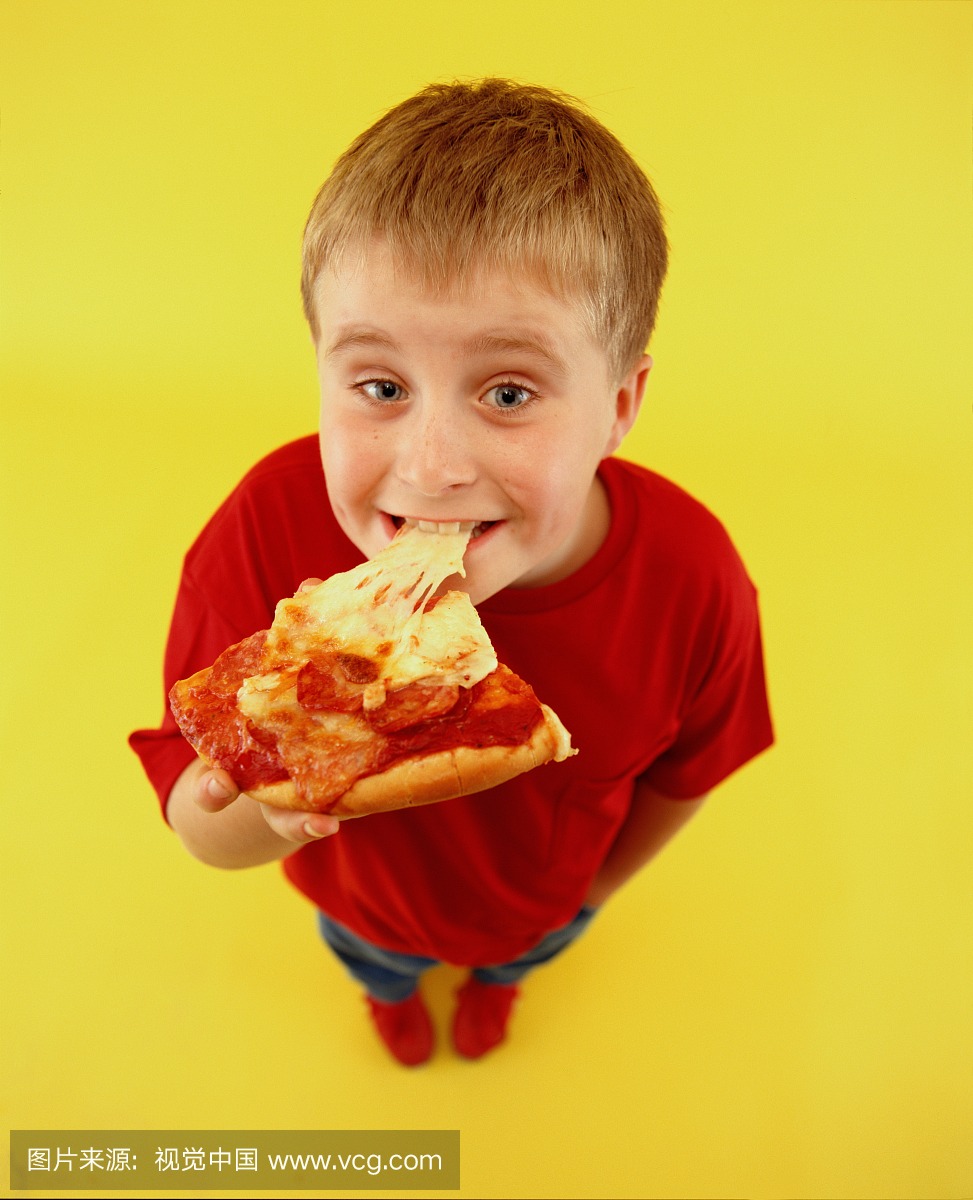 男孩(7-9)吃大片披萨,高架视角(广角)