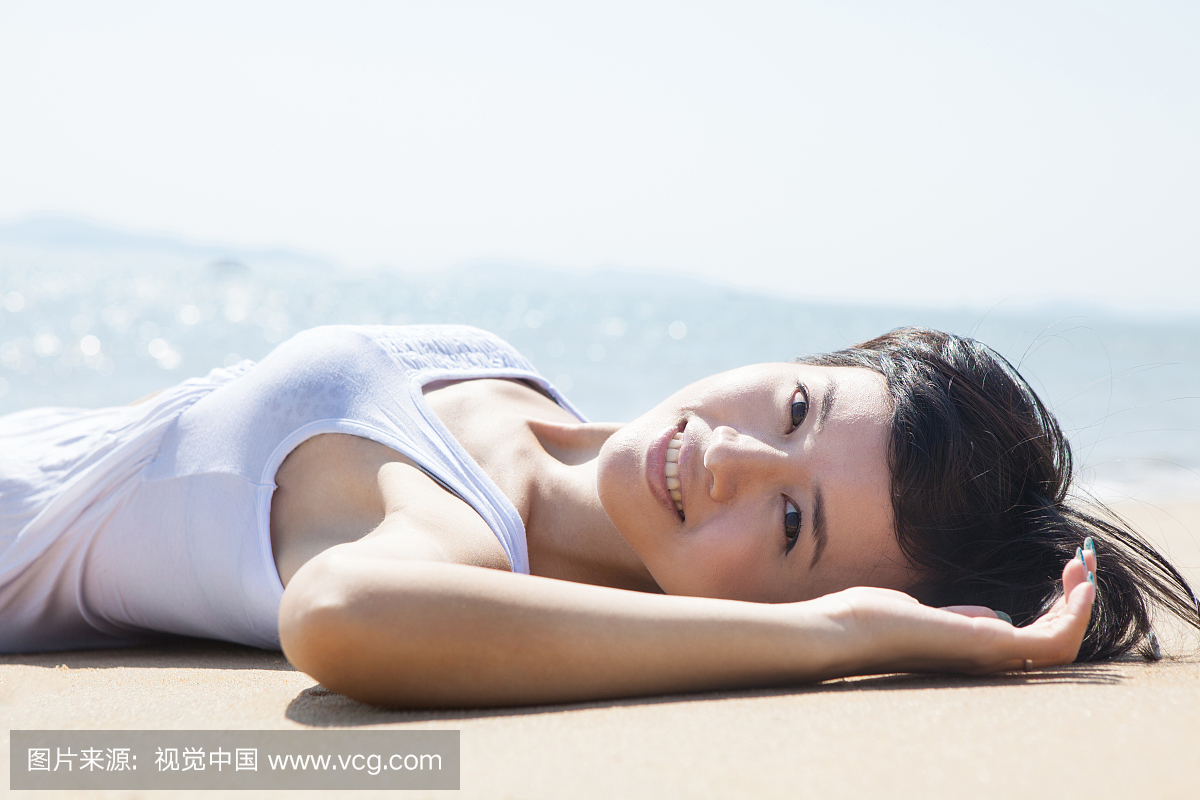 年轻女子躺在在沙滩上晒太阳