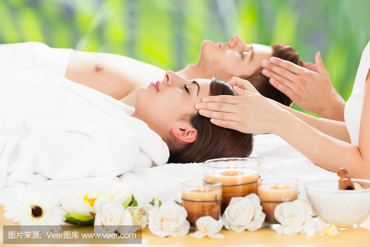 轻松的夫妇接受头部按摩在水疗中心